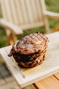 Well done dry-aged rib eye steak on a cutting board outside in the summer sun