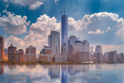 City at waterfront against cloudy sky