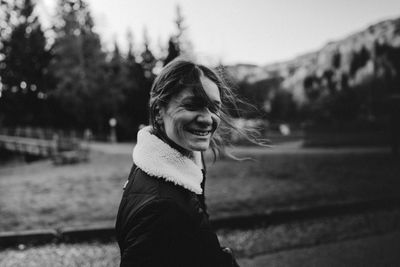 Portrait of young woman looking away against mountain