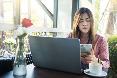 Young woman using laptop on table at home