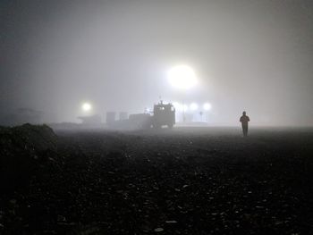 Silhouette of city on field against sky at night