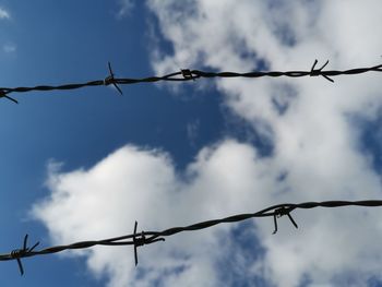 Low angle view of barbed wire against sky