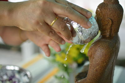 Close-up of hand pouring water on buddha statue
