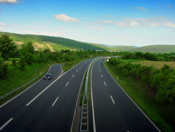 Empty country road along landscape against sky