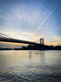 View of suspension bridge over river at sunset