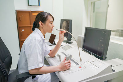 Side view of woman using phone while sitting on table