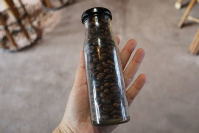 Cropped hand holding roasted coffee beans in jar 