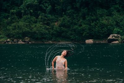 Man surfing in lake against trees