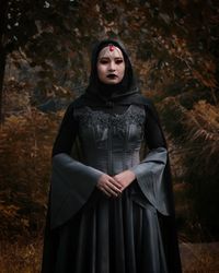 Portrait of young woman in halloween costume standing at forest during autumn
