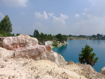 Scenic view of rocks by trees against sky