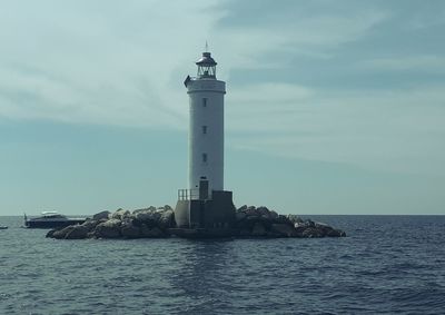 Lighthouse by sea against sky