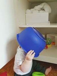 Baby playing with blue container at home