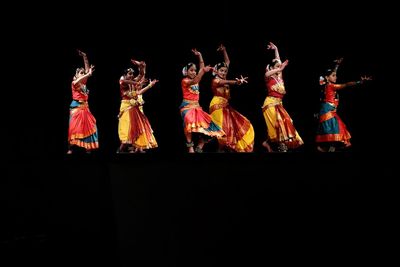 Group of people dancing against black background