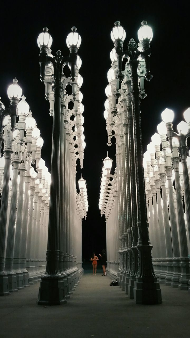 built structure, illuminated, architecture, night, lighting equipment, street light, the way forward, architectural column, in a row, building exterior, column, arch, diminishing perspective, street, low angle view, history, travel destinations, incidental people, pillar, road