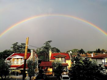 Rainbow over buildings in city against sky