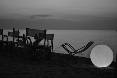 Abandoned chair on beach against sky