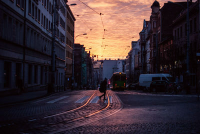 Tram and other land vehicles by buildings at dusk