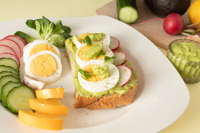 Avocado toast with guacamole, cucumber, radish and sliced boiled egg. ingredients for avocado salad. 