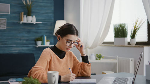 Young woman using laptop while sitting at home