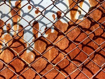 Full frame shot of chainlink fence against rusty wall