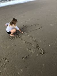 High angle view of girl drawing on sand at beach