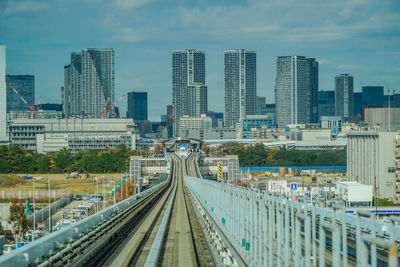 Railroad tracks amidst buildings in city against sky