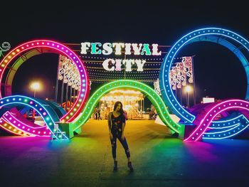 Full length of man standing at illuminated amusement park