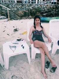 Portrait of woman sitting on chair at beach