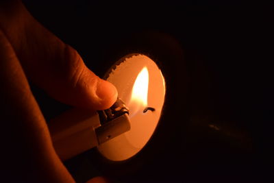 Close-up of hand igniting candle