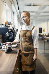 Young woman standing by coffee at cafe