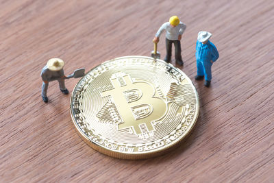 High angle view of male figurines amidst bitcoin on table