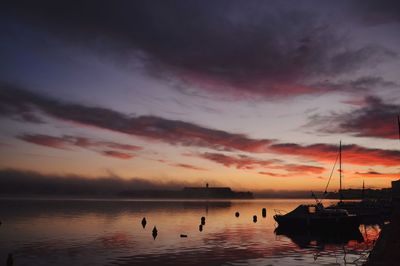 Silhouette of boats in sea at sunset