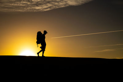 Silhouette man walking against sky during sunset