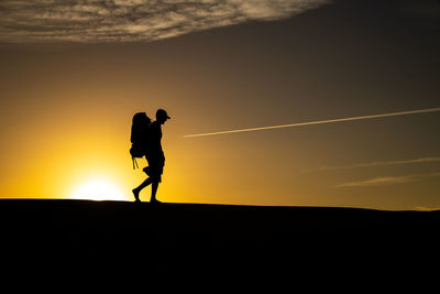 Silhouette man standing against sky during sunset