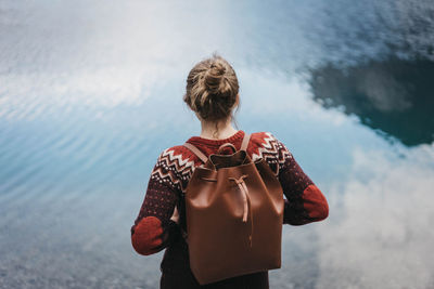 Rear view of woman standing against lake