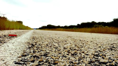 Surface level of pebble field against clear sky