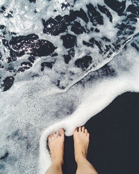 Low section of person standing in water