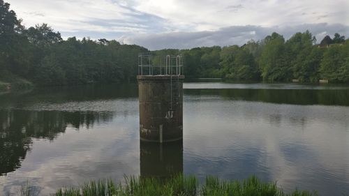 Wooden posts in lake against sky