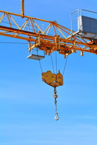 Low angle view of crane against clear blue sky