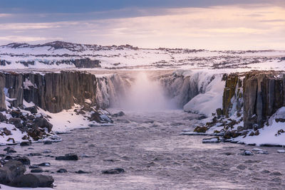 Scenic view of waterfall against sky during winter