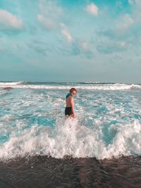 Rear view of man standing in sea against sky