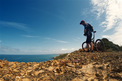 Rear view of man riding bicycle on beach against sky
