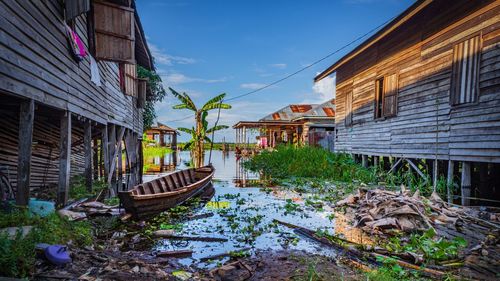 Abandoned house by building against sky