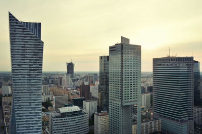 Modern buildings in city against sky during sunset