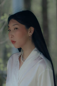 Portrait of young woman standing against wall