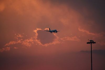 Low angle view of silhouette airplane against sky during sunset