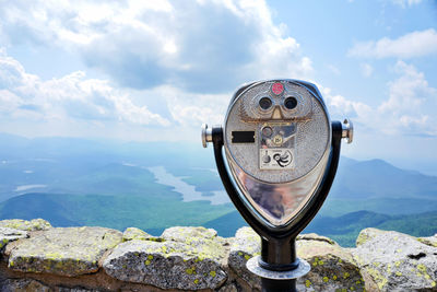 Close-up of coin-operated binoculars against sky on mountain top. travel and exploring background.