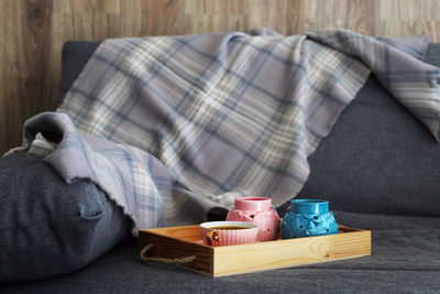 Coffee cup by fabric in serving tray on sofa at home