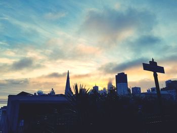 Low angle view of silhouette skyscraper against sky during sunset