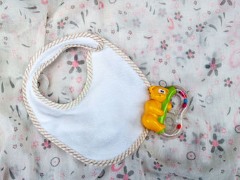 High angle view of baby bib and toy on fabric